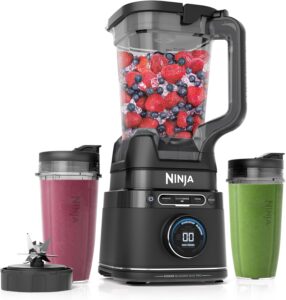 Ninja Power Blender filled with berries and two smoothie cups on the side.