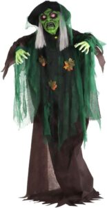 Life-size animated witch decoration with green face and flowing robes.